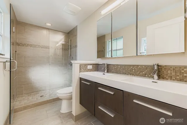 a bathroom with a granite countertop sink a toilet a mirror and shower