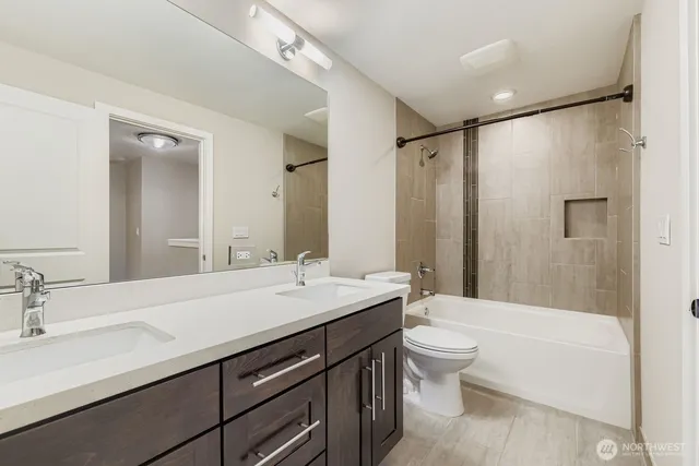 a bathroom with a double vanity sink toilet mirror and bathtub