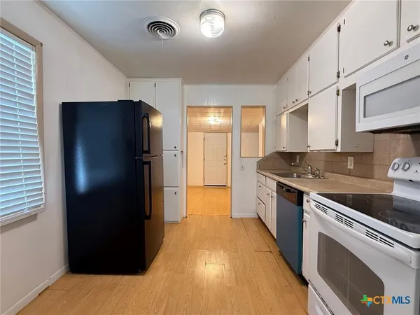 a large kitchen with stainless steel appliances granite countertop a refrigerator and a sink