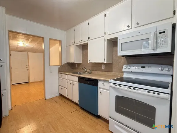 a kitchen with granite countertop white cabinets and white appliances