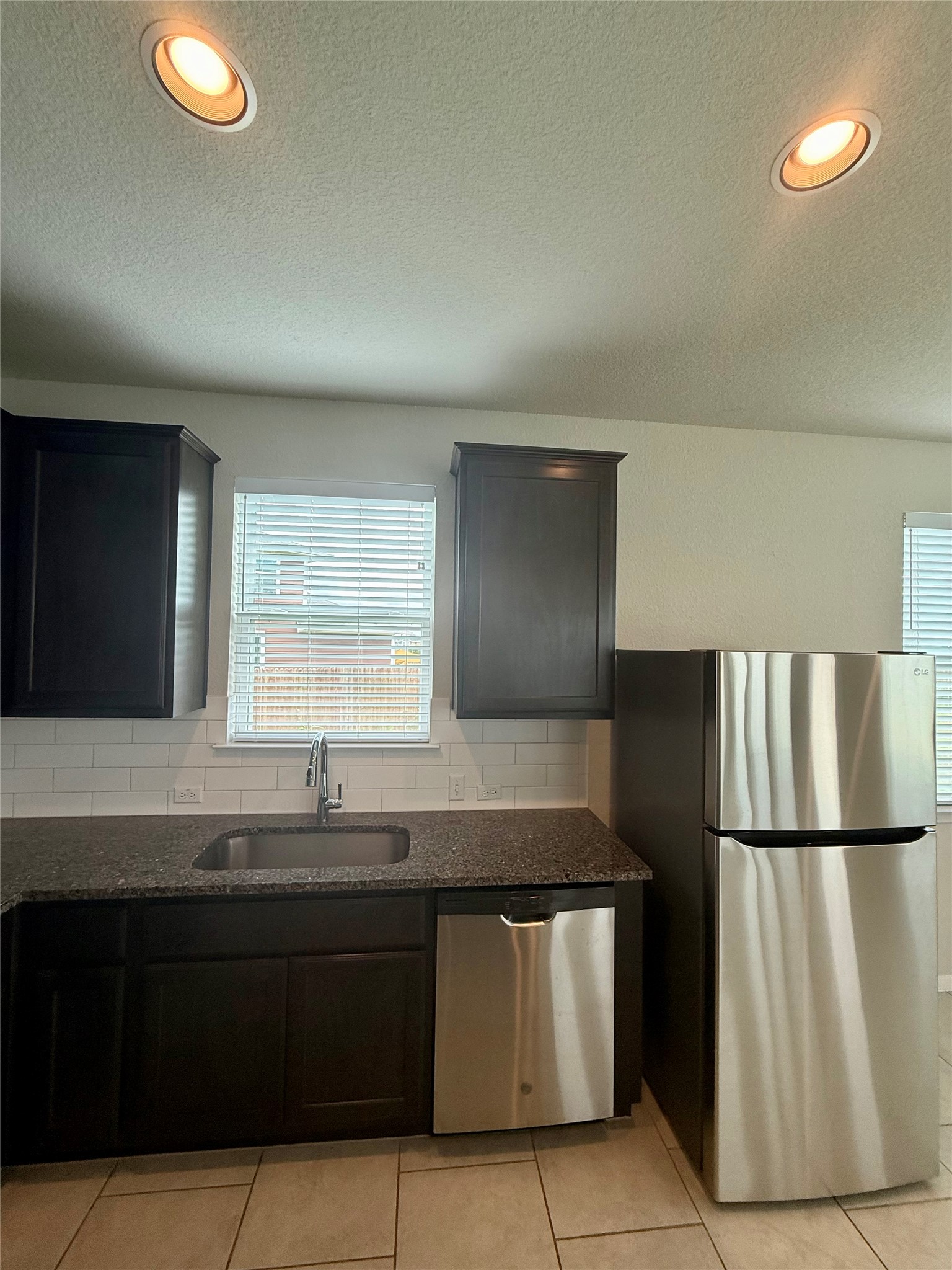 212 Lake Placid Run Elgin, TX 78621 - Photo 7 of 27 A well-appointed kitchen showcasing elegant dark cabinetry, granite countertops, and modern stainless steel appliances.
