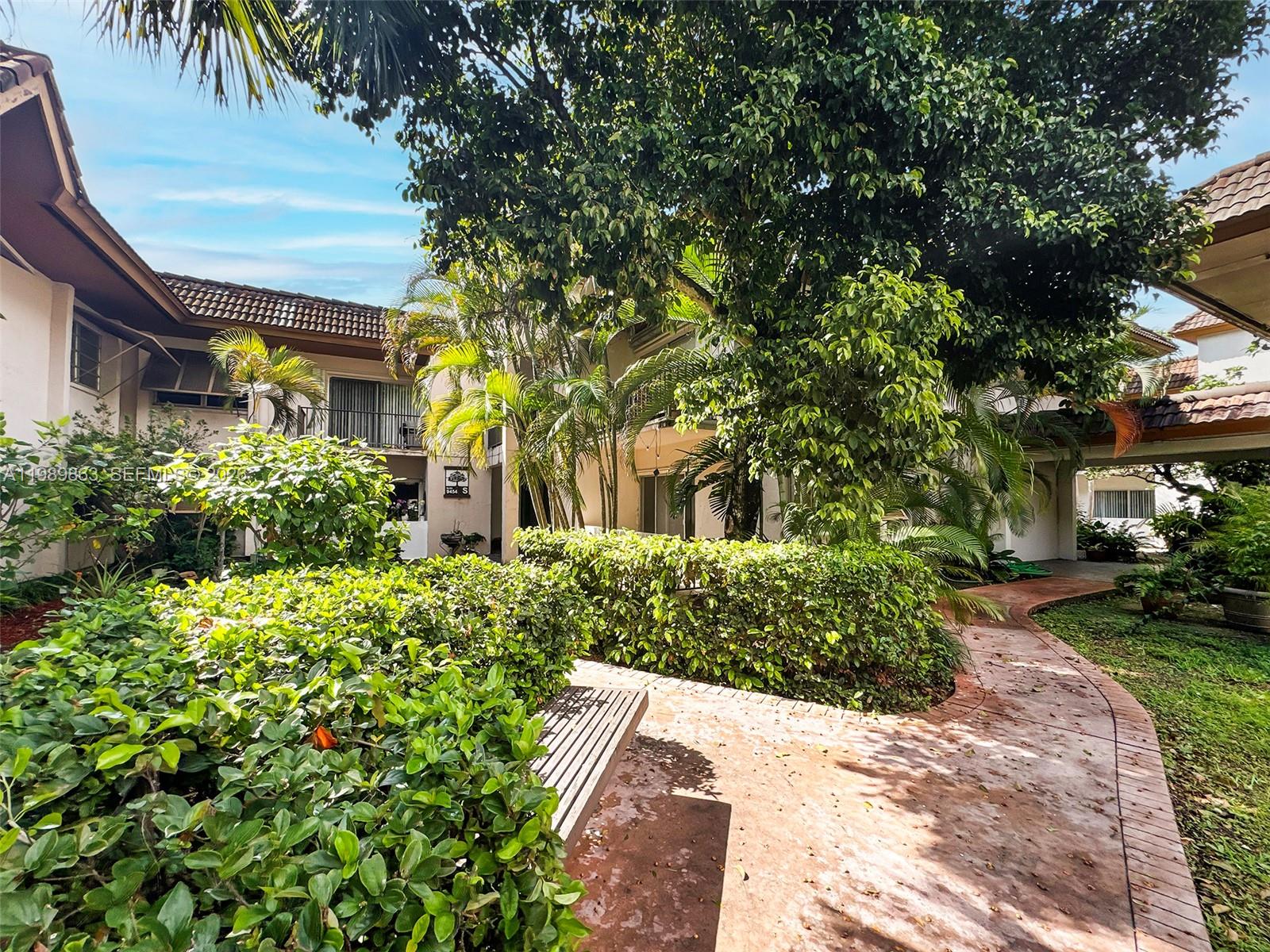 9454 Southwest 77th Avenue, Unit S1 Miami, FL 33156 - Photo 1 of 20 a front view of a house with a yard and a garden