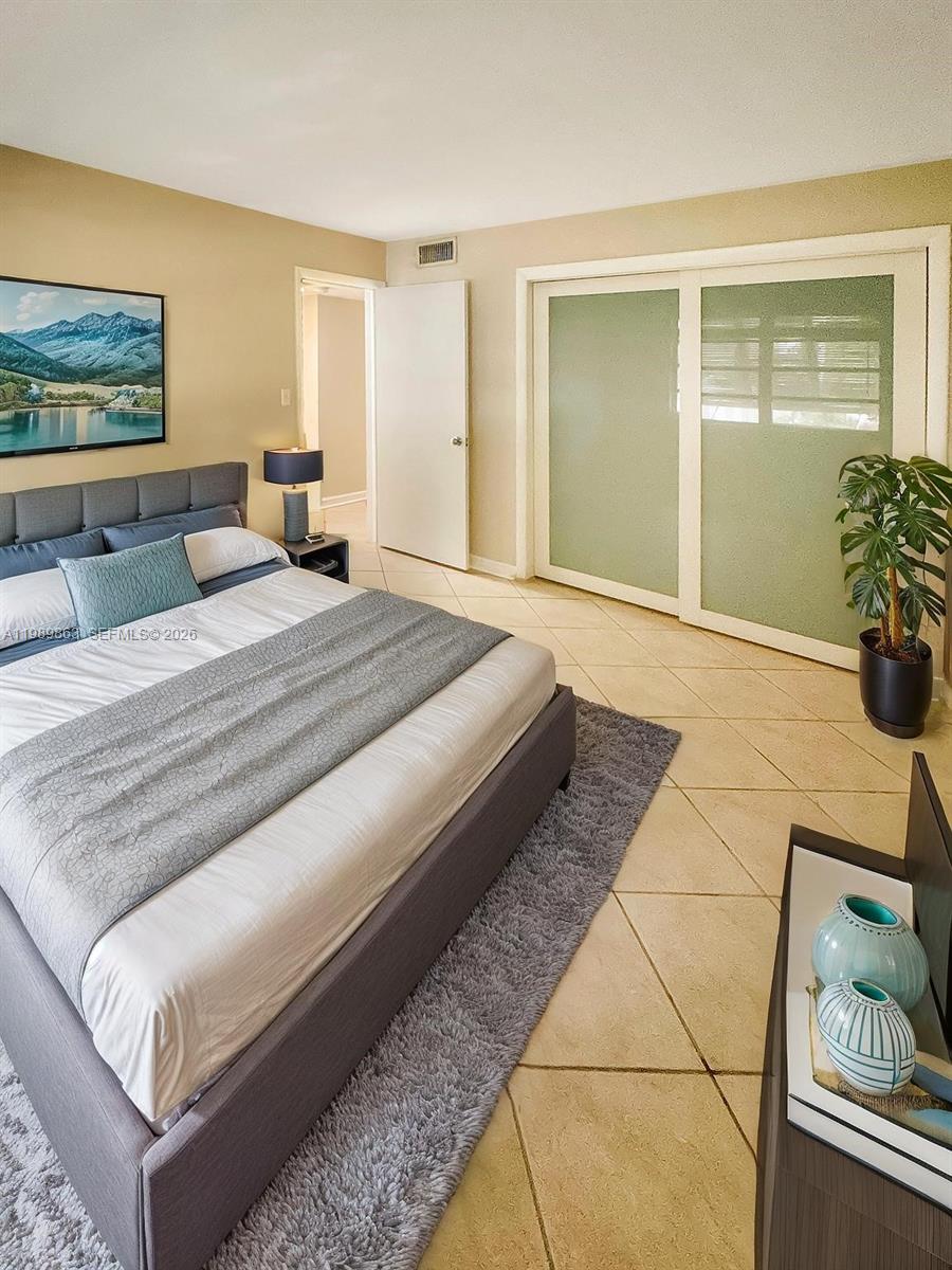 9454 Southwest 77th Avenue, Unit S1 Miami, FL 33156 - Photo 14 of 20 a spacious bedroom with a bed and a painting on the wall