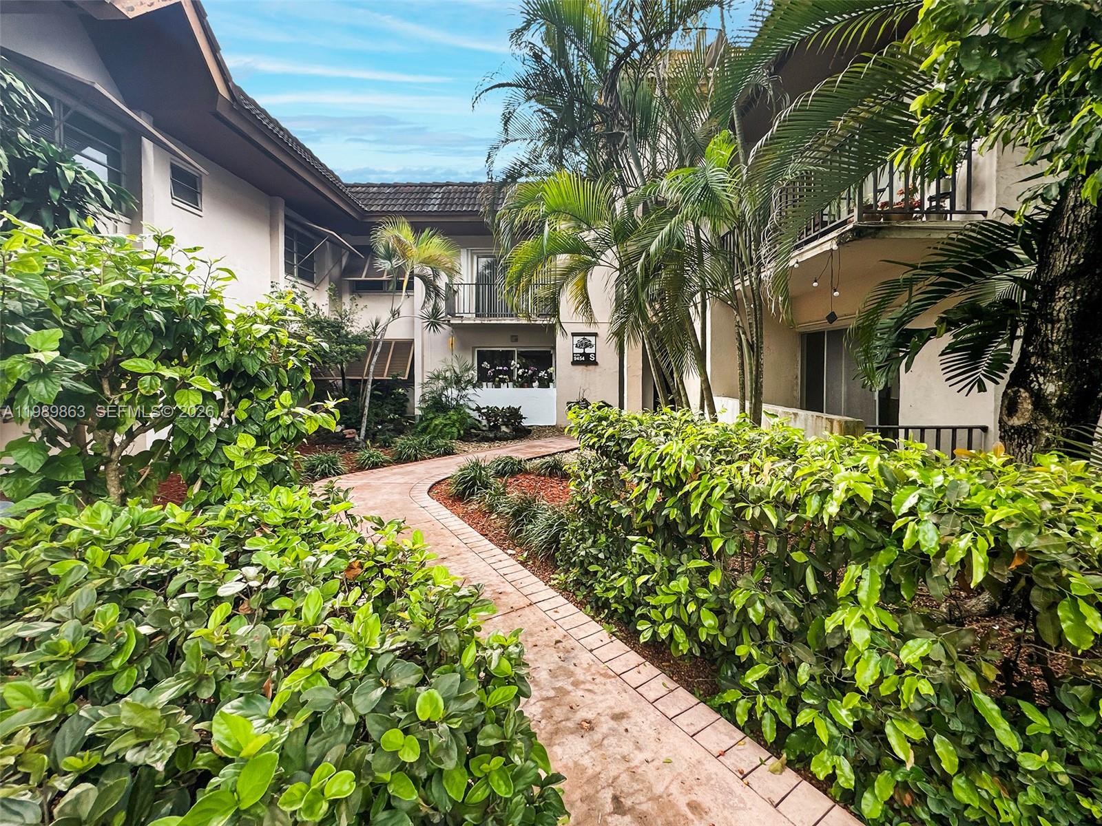 9454 Southwest 77th Avenue, Unit S1 Miami, FL 33156 - Photo 17 of 20 a front view of a house with a yard and potted plants