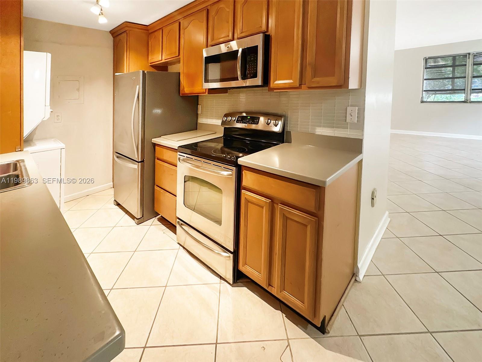 9454 Southwest 77th Avenue, Unit S1 Miami, FL 33156 - Photo 4 of 20 a kitchen with stainless steel appliances a refrigerator a stove a microwave a sink and cabinets