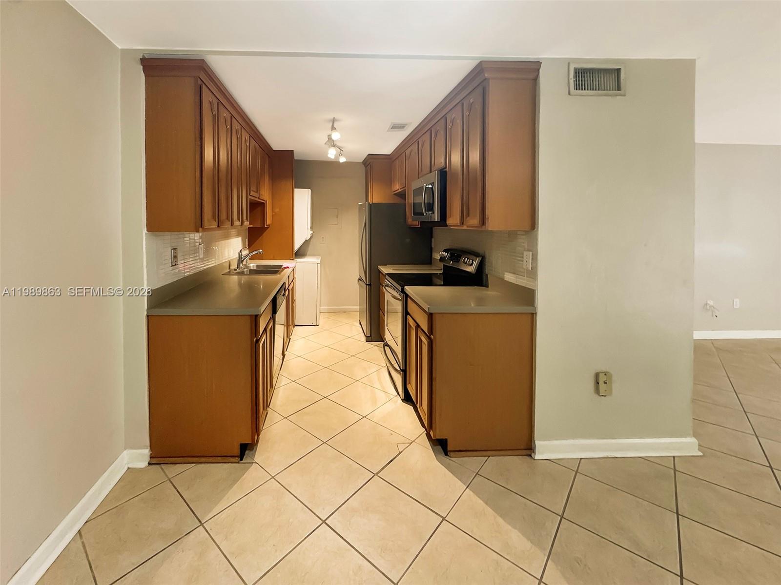 9454 Southwest 77th Avenue, Unit S1 Miami, FL 33156 - Photo 6 of 20 a kitchen with stainless steel appliances a refrigerator sink and stove