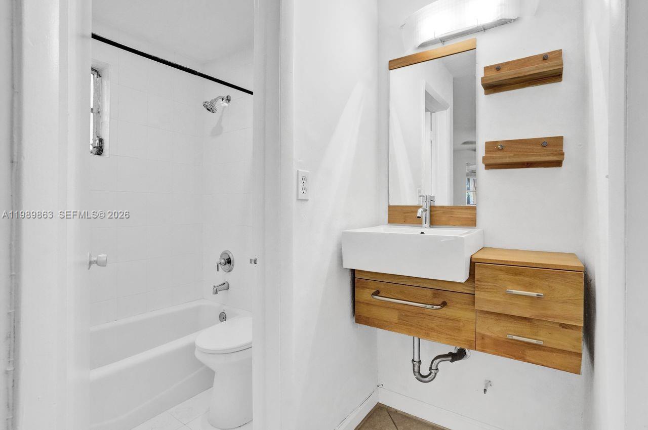 9454 Southwest 77th Avenue, Unit S1 Miami, FL 33156 - Photo 10 of 20 a bathroom with a sink mirror bathtub and toilet