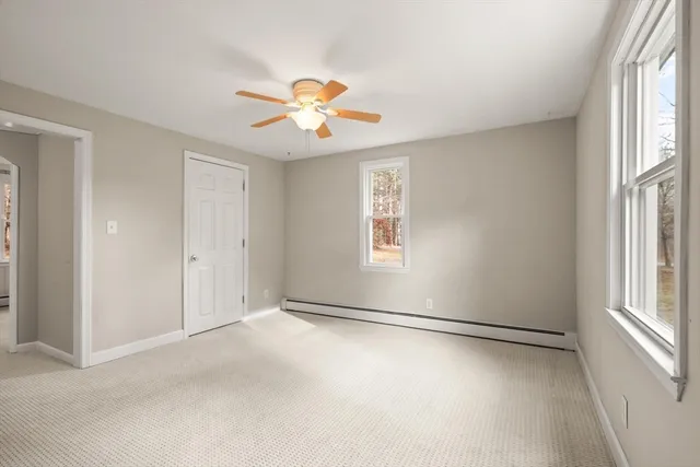 an empty room with windows and chandelier fan