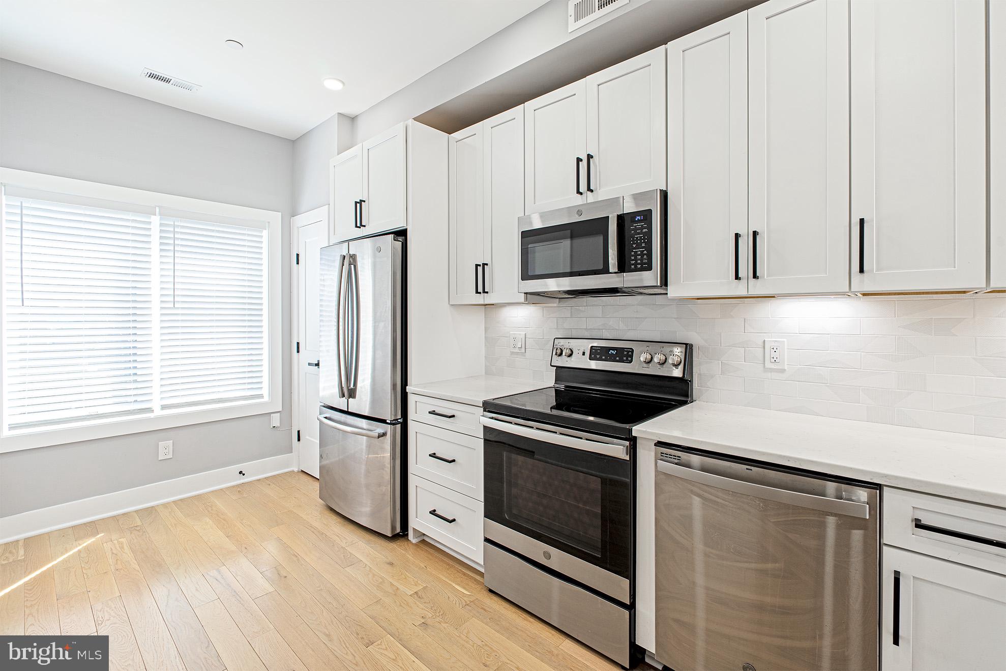 1219 Wylie Street Northeast, Unit 2 Washington, DC 20002 - Photo 12 of 29 a kitchen with stainless steel appliances white cabinets and a stove top oven