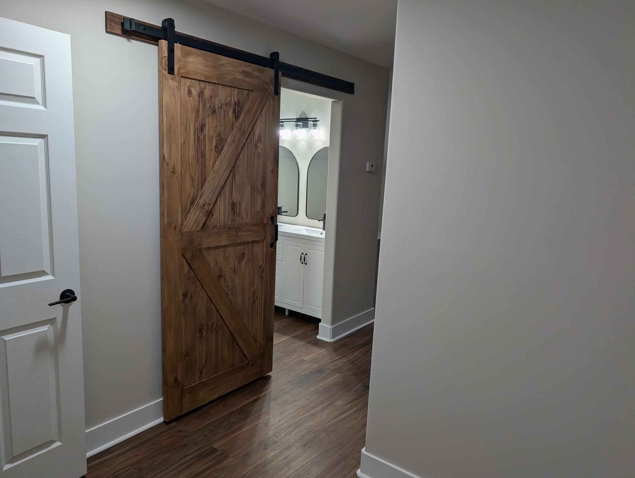 3540 Portersville Road Atoka, TN 38004 - Photo 24 of 37 Wood-finish flooring, white walls, and a modern barn door with black hardware
