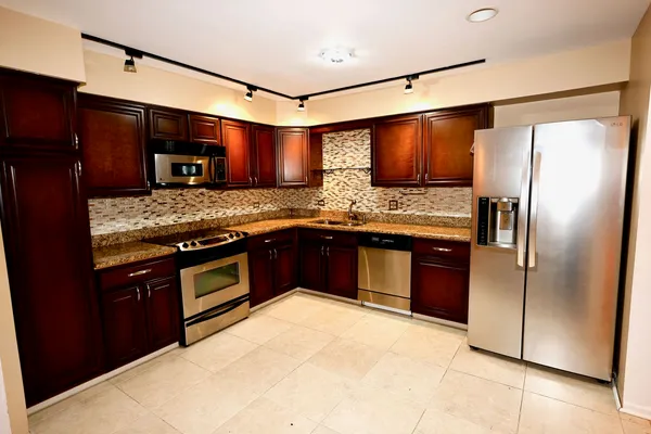 a kitchen with stainless steel appliances granite countertop a refrigerator and a stove
