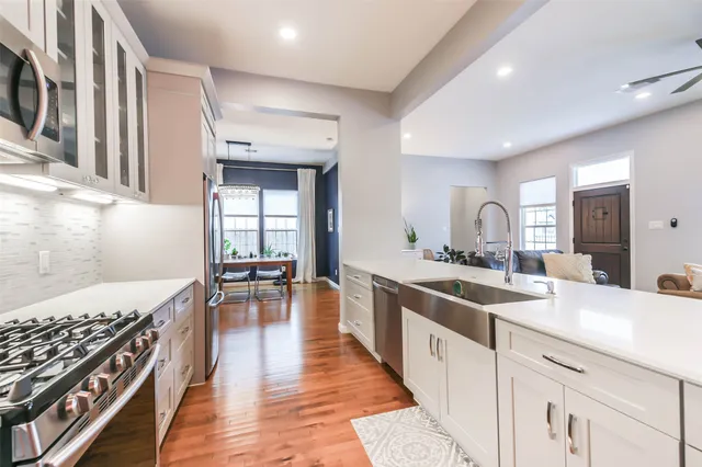 a kitchen with a stove a sink and wooden floor