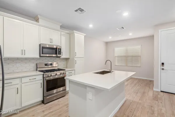 a kitchen with kitchen island a sink stainless steel appliances and white cabinets