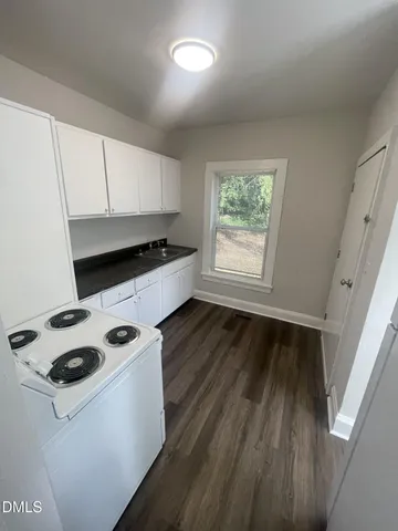 a kitchen with microwave a stove and wooden floor