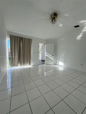 a view of an empty room and chandelier fan