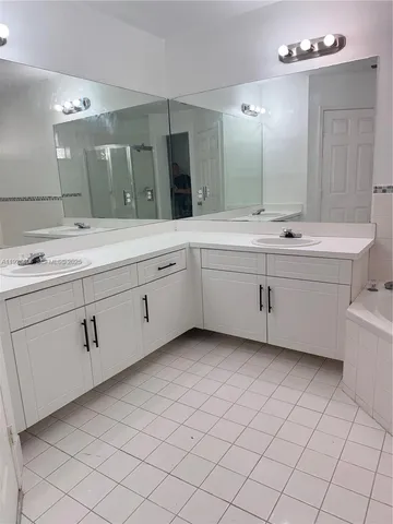 a bathroom with a double vanity sink mirror and bathtub