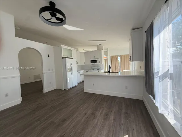 a kitchen with stainless steel appliances granite countertop a stove a refrigerator and a wooden floor