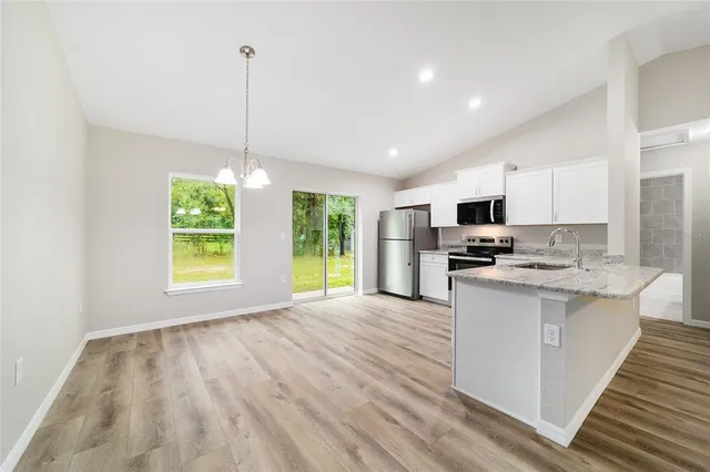 a kitchen with stainless steel appliances kitchen island granite countertop a refrigerator a stove top oven a sink dishwasher and a wooden cabinets