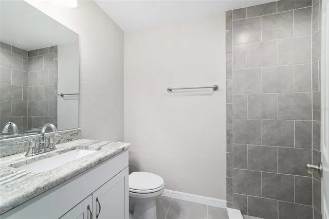a bathroom with a granite countertop sink a toilet and a mirror