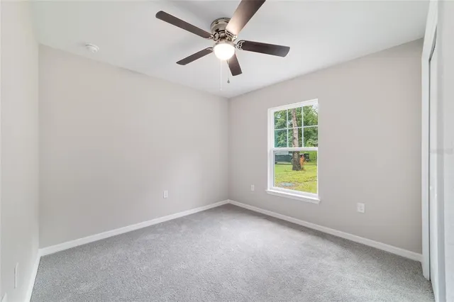 an empty room with ceiling fan and windows