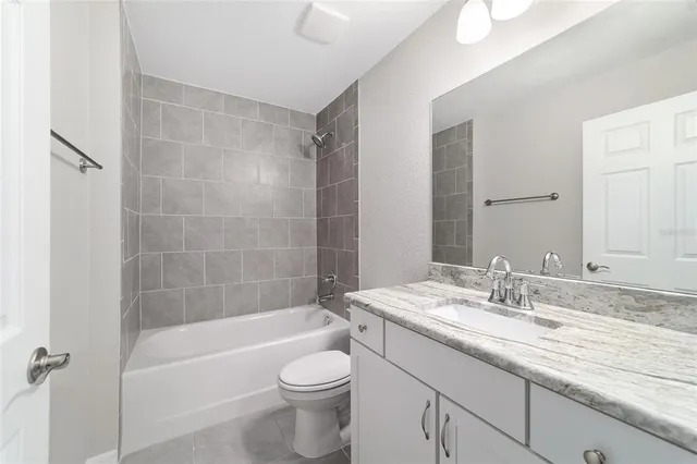a bathroom with a granite countertop bathtub shower sink vanity mirror and toilet
