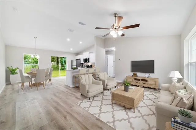 a living room with furniture and a flat screen tv with kitchen view