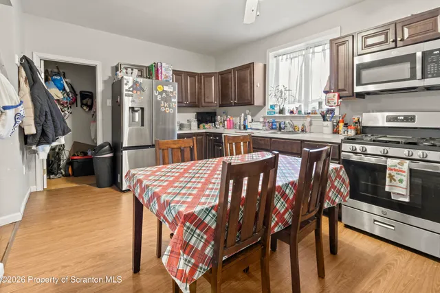 a kitchen with stainless steel appliances granite countertop a stove top oven a sink dishwasher and a refrigerator with wooden floor