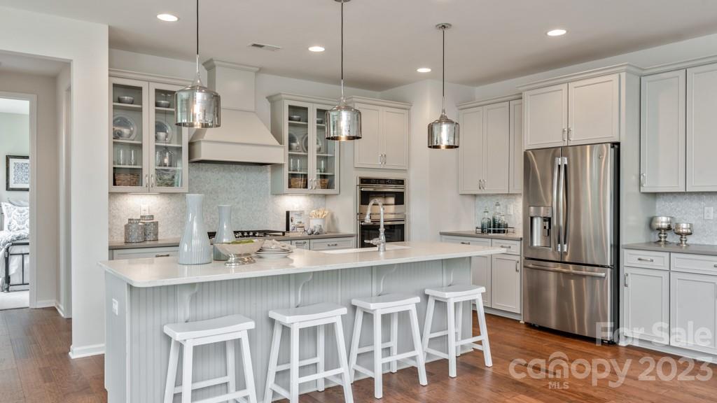 13219 Chopin Ridge Road Huntersville, NC 28078 - Photo 10 of 37 a kitchen with stainless steel appliances kitchen island granite countertop a refrigerator a stove a sink and white cabinets with wooden floor
