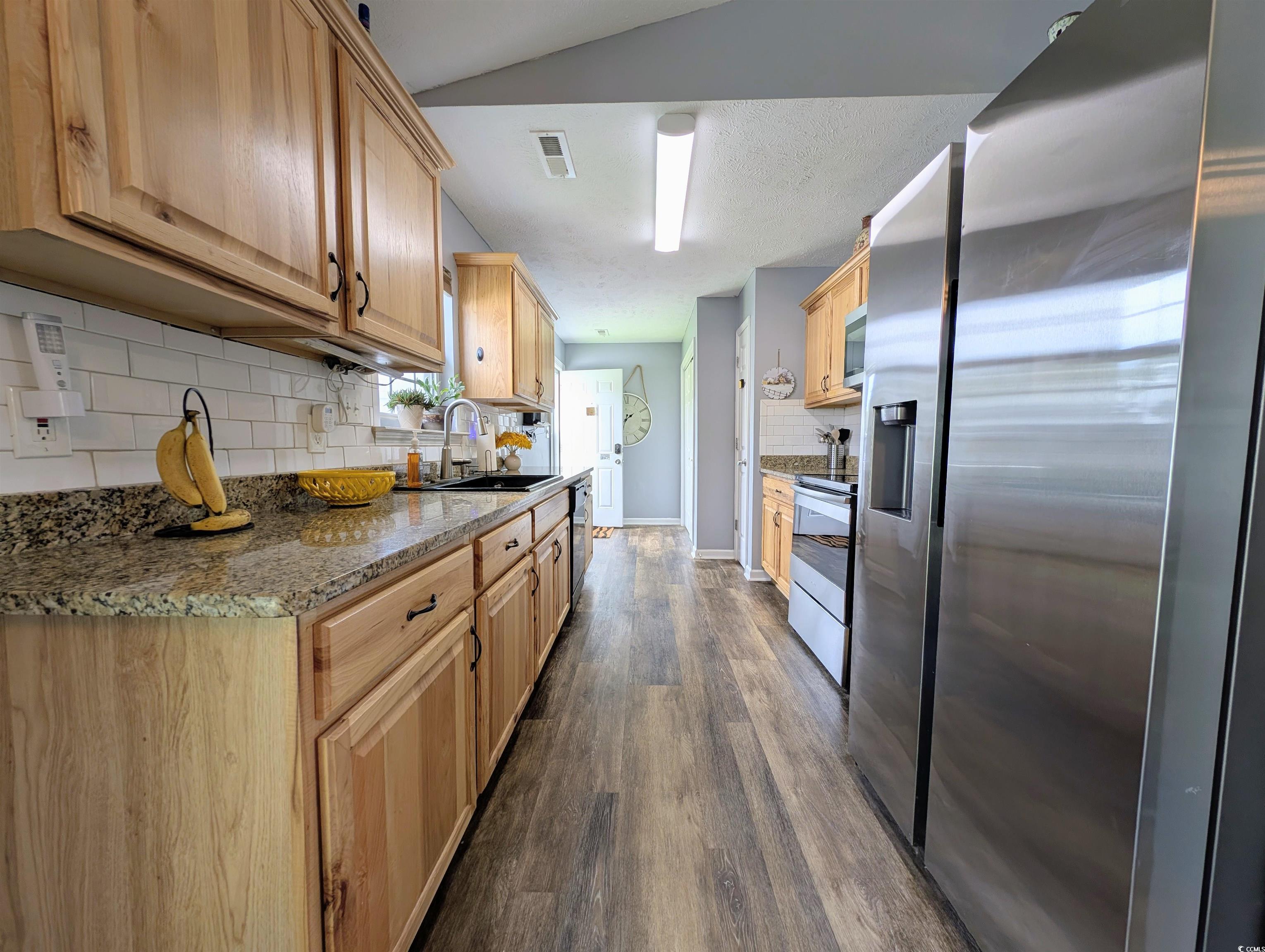 1013 Autumn Drive Murrells Inlet, SC 29576 - Photo 14 of 36 Galley kitchen with stainless steel appliances, light stone countertops, decorative backsplash, and dark wood-style flooring