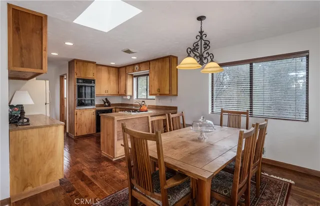 a kitchen with kitchen island a large counter top space appliances and a chandelier