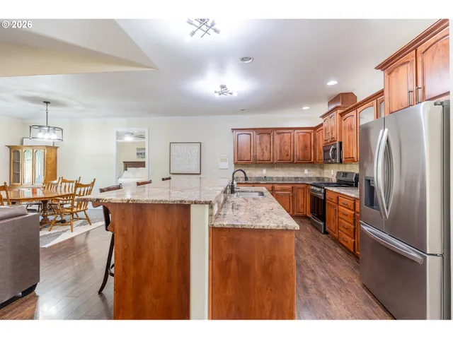 a kitchen with stainless steel appliances granite countertop a refrigerator a sink dishwasher a oven with white cabinets and wooden floor