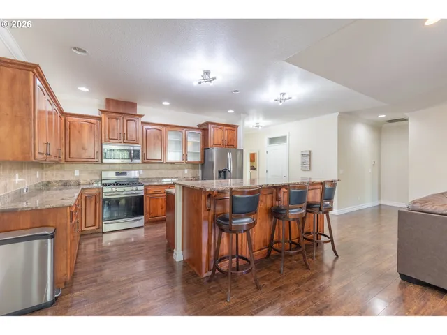 a kitchen with stainless steel appliances kitchen island granite countertop a table chairs and a refrigerator