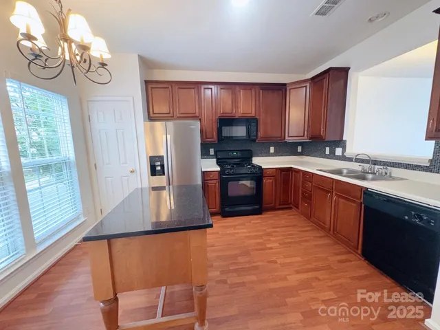 a large kitchen with stainless steel appliances granite countertop a stove a sink dishwasher and a refrigerator