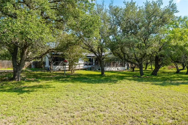 a view of a house with a big yard and large trees