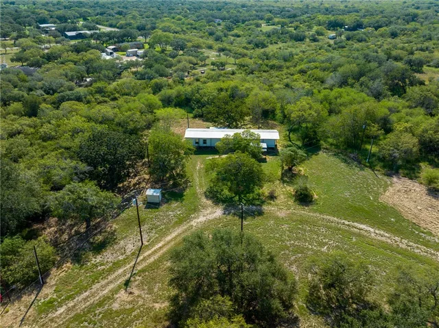 an aerial view of residential houses with outdoor space and trees