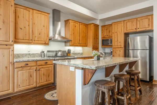 a kitchen with stainless steel appliances granite countertop a stove top oven a sink dishwasher and wooden floor