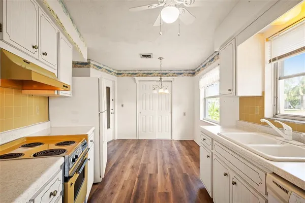 a view of a kitchen with a sink dishwasher a stove and wooden floor