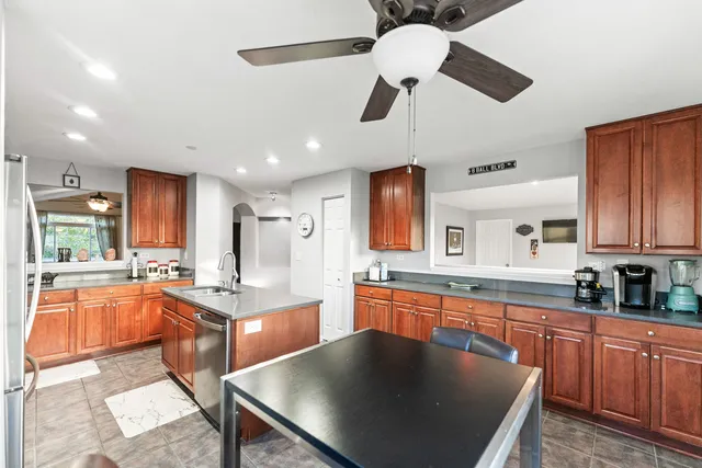 a large kitchen with stainless steel appliances granite countertop a sink dishwasher a stove and refrigerator with wooden floor