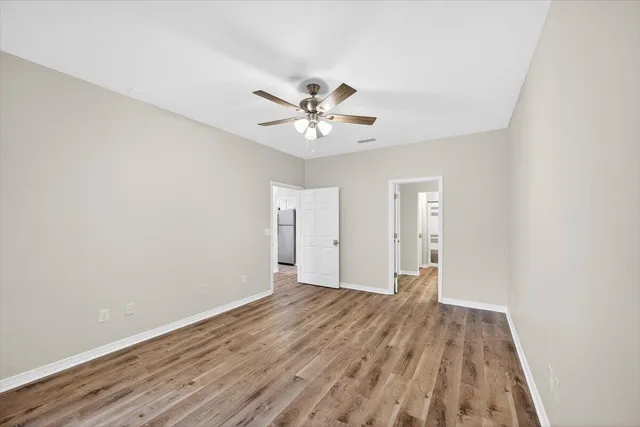 a view of a room with wooden floor and a ceiling fan