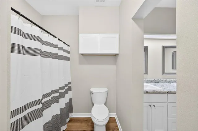 a bathroom with a granite countertop toilet and a sink