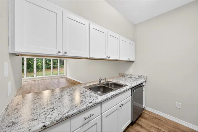 a kitchen with granite countertop white cabinets and a sink