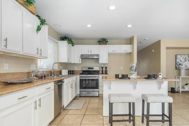 a kitchen with stainless steel appliances granite countertop a table chairs sink and cabinets
