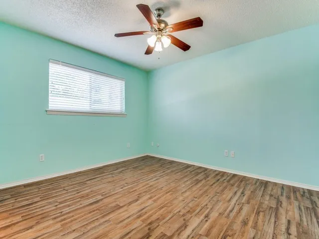an empty room with wooden floor and a ceiling fan