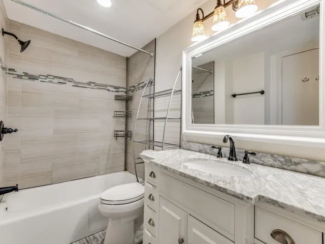 a bathroom with a granite countertop sink a toilet and shower