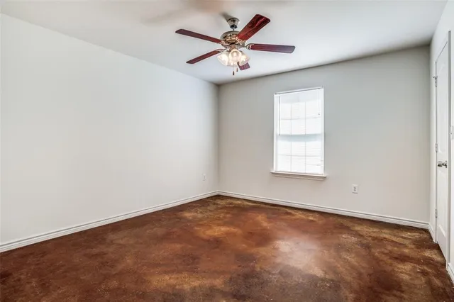 an empty room with windows and chandelier fan