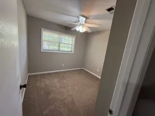 an empty room with windows and ceiling fan