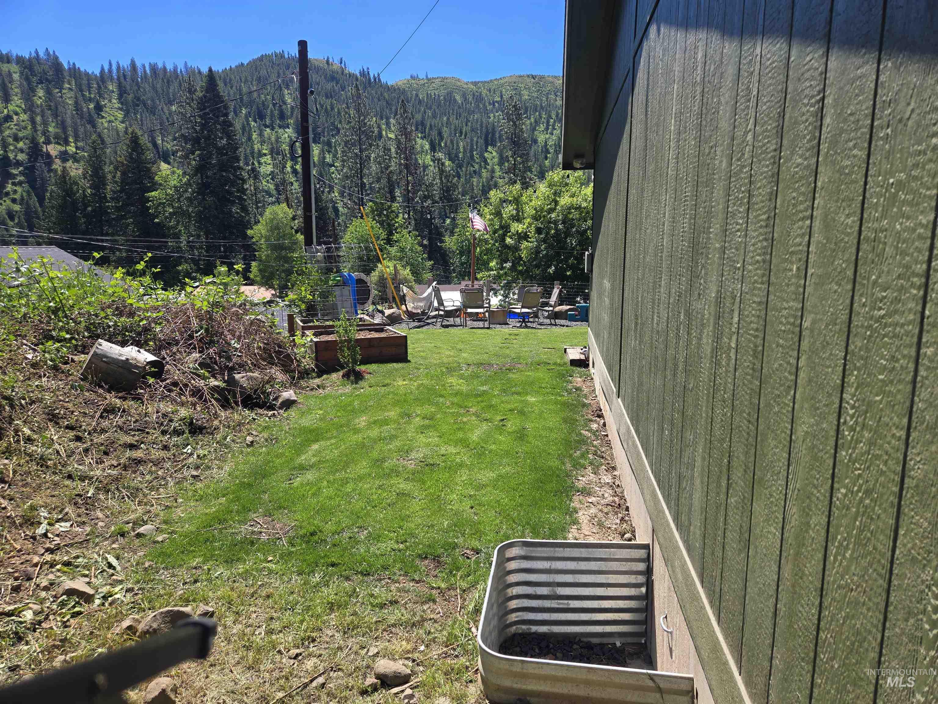 174 Konkolville Road Orofino, ID 83544 - Photo 39 of 43 Green vertical siding exterior with a window well and a manicured lawn