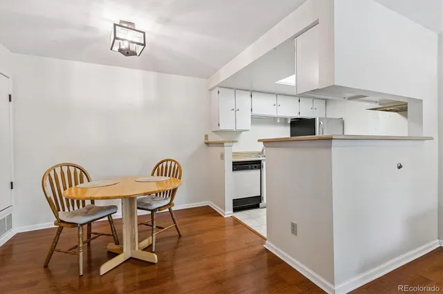 a kitchen with stainless steel appliances kitchen island a dining table chairs and a refrigerator