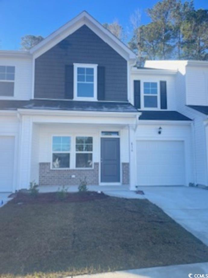 View of front of home with driveway, brick siding, a garage, and a front yard