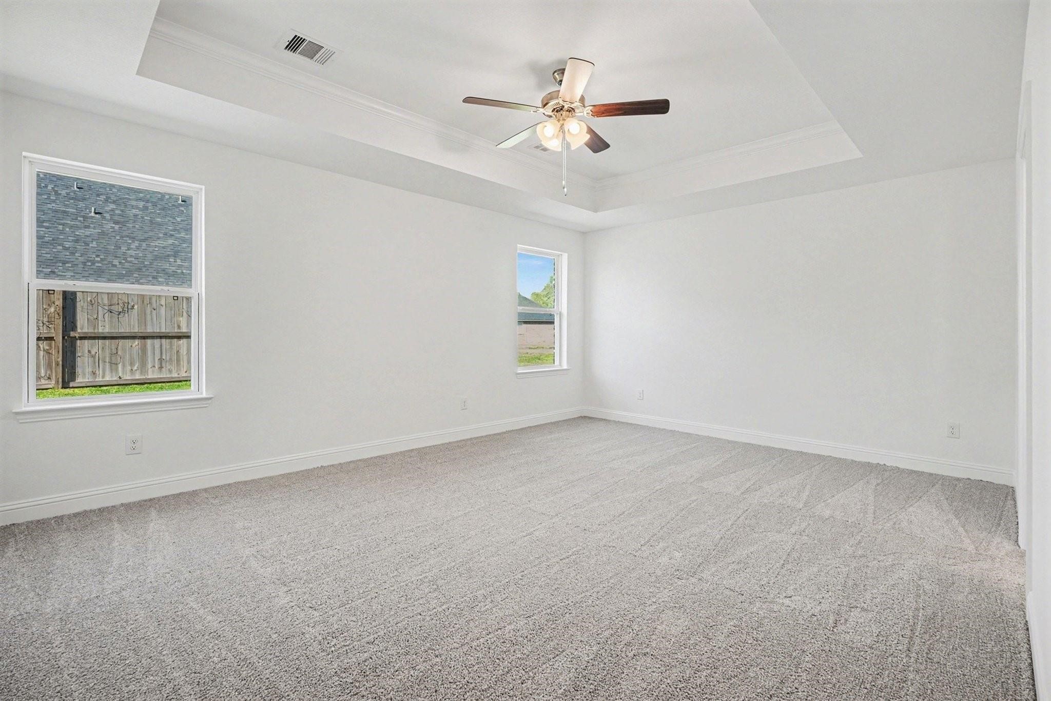 an empty room with windows and fan